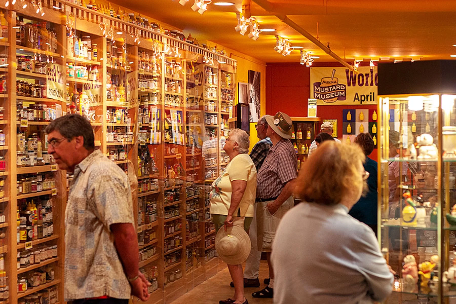 Visitors walking the museum’s long display of mustard jars