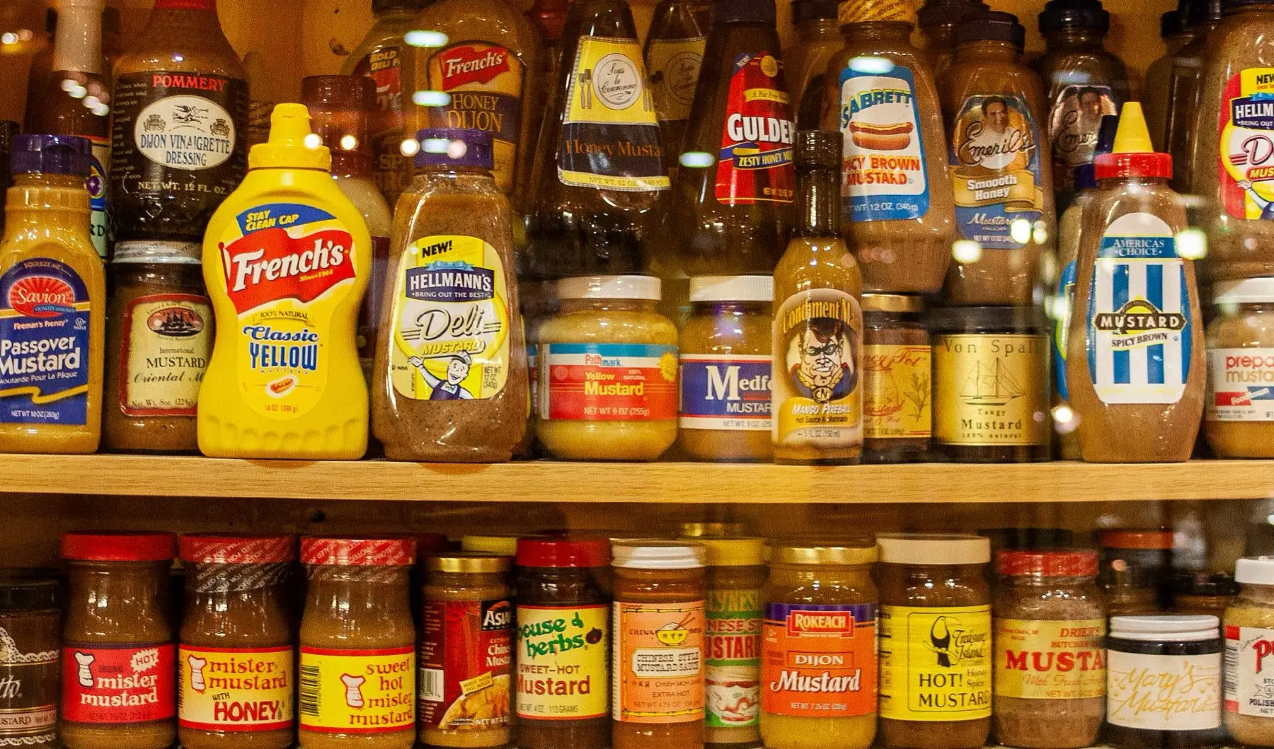 Rows of real mustard jars and bottles behind glass at the National Mustard Museum